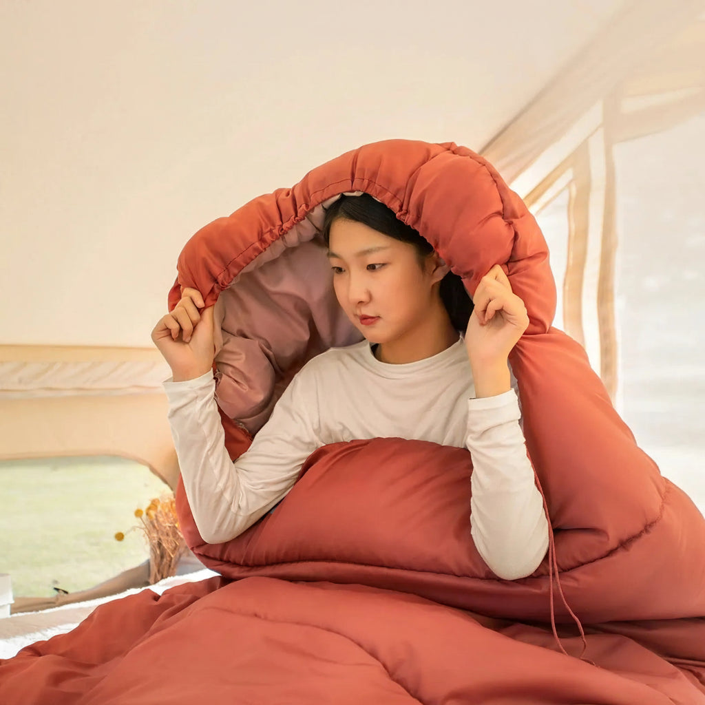 Model tucked inside a BISINNA BL018 sleeping bag in a red colour