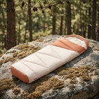 A BISINNA BL077 sleeping bag on a rock with a forest background.