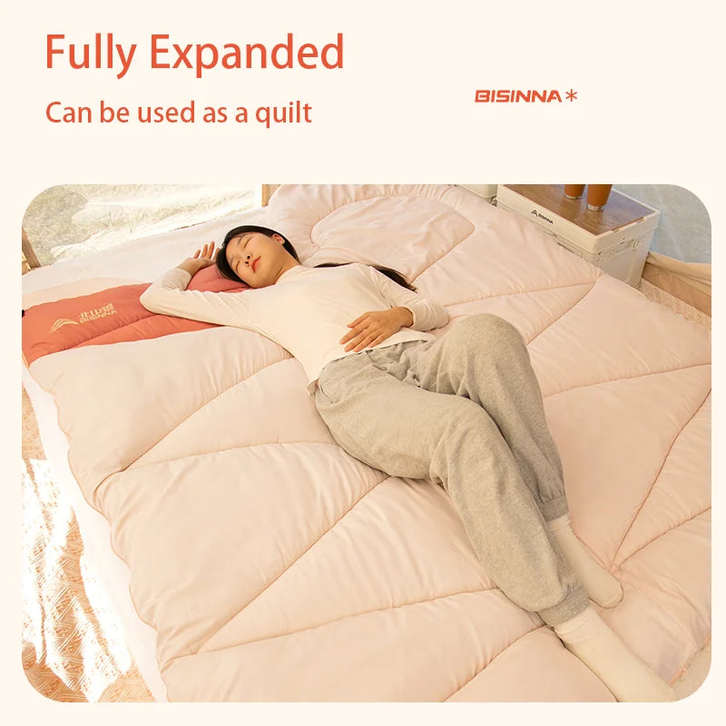 Person lying on a fully expanded BISINNA sleeping bag with text indicating it can be used as a quilt.