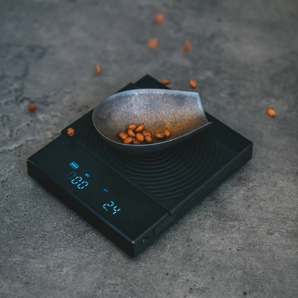TIMEMORE Black Mirror Coffee Scale with a bowl of coffee beans on a gray surface