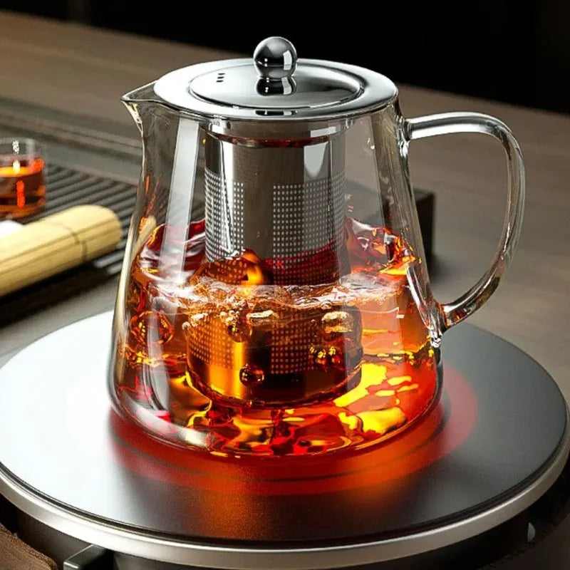 Borosilicate Clear glass teapot with metal lid and infuser on a dark surface