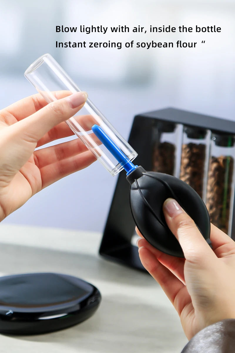 Person using a small black and blue device to blow air into a clear bottle with text about soybean flour.