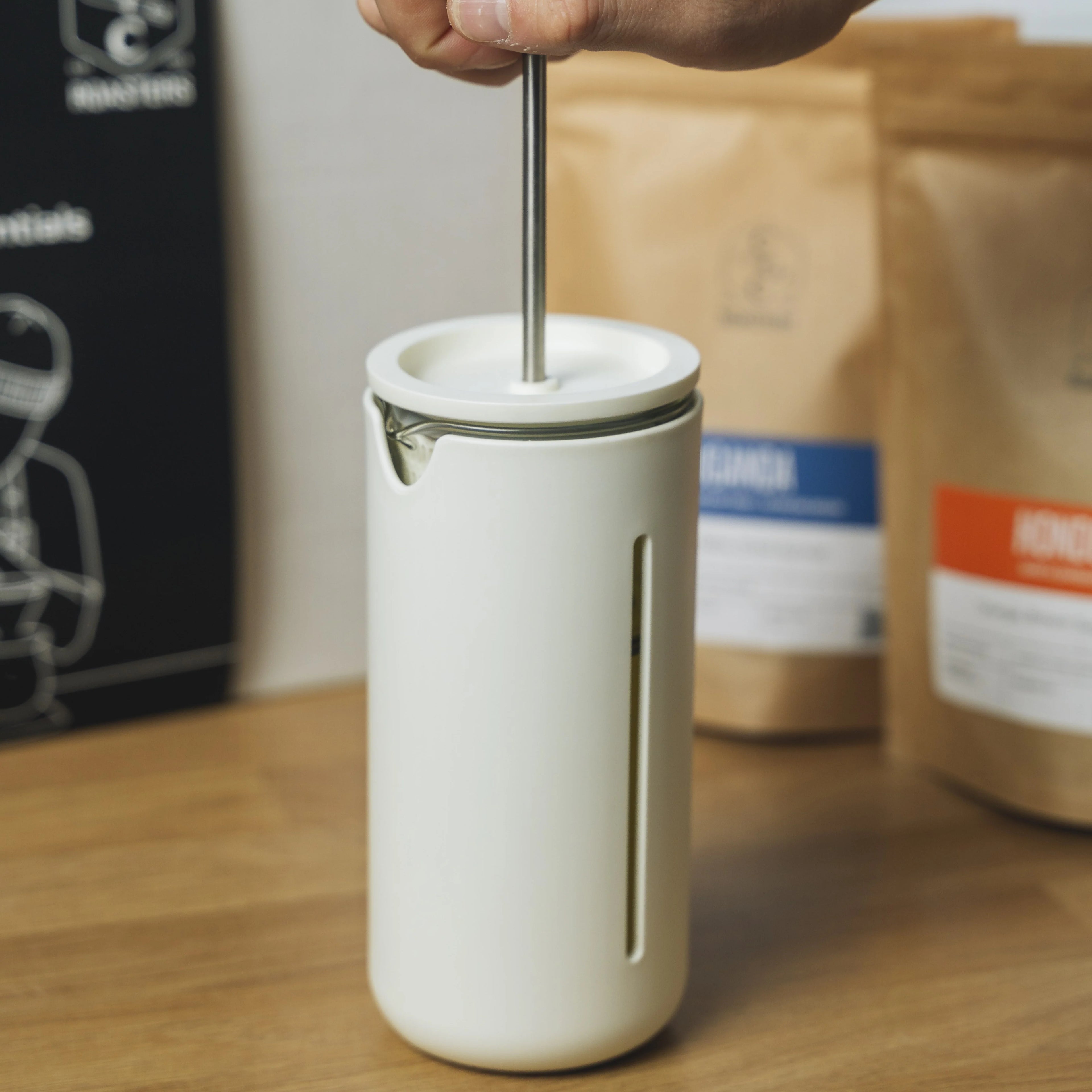 TIMEMORE U French Press being used, with coffee bags in the background.