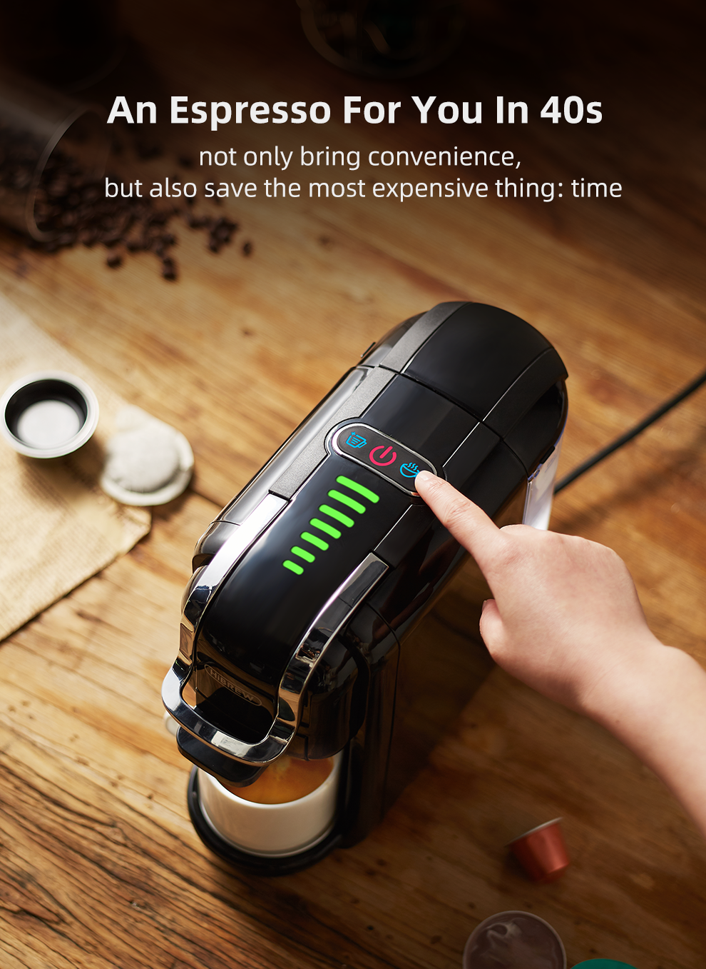 H2B Black espresso machine on a wooden surface with a hand pressing a button, surrounded by coffee beans and a cup.