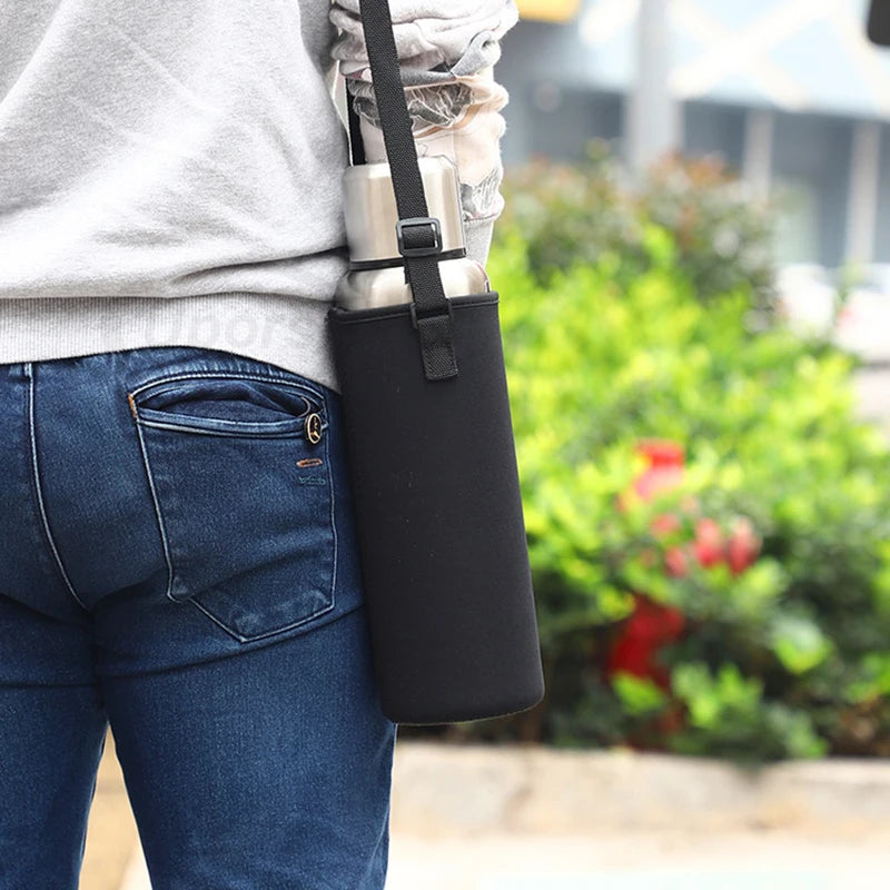Person wearing a black insulated drink holder on a blurred outdoor background