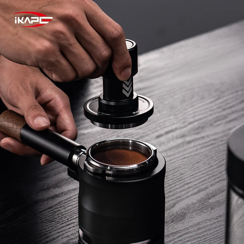 Person using a coffee tamping tool on a wooden surface with iKAPE branding.