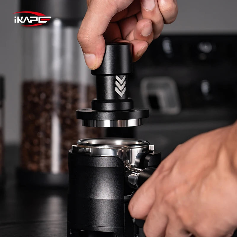 An iKAPE tamper about to compress coffee ground in a handle with a blurred background shot. 