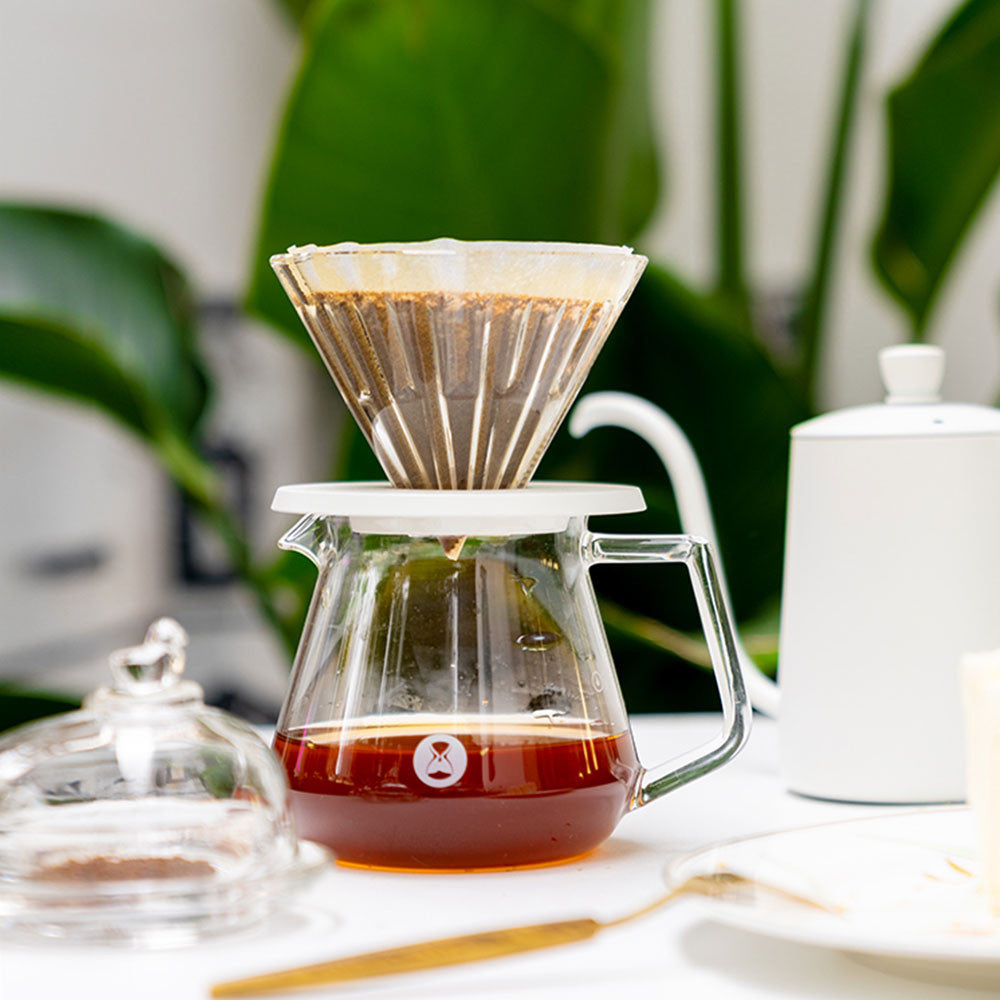 Coffee brewing process with a glass carafe and paper filter on a blurred background